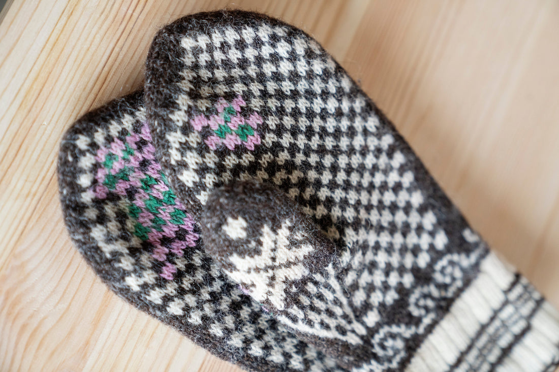 Reparerte ullvotter i brunt og hvitt ullgarn med grønn og rosa reparasjon