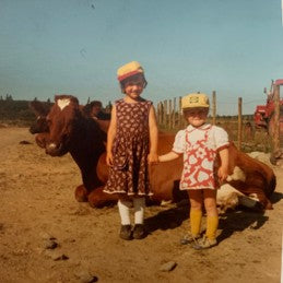 Turi Rudningen holden lillesøster i hånda. De står fremfor en ku og gammel traktor på stølen. En barndom som ga gode verdier.