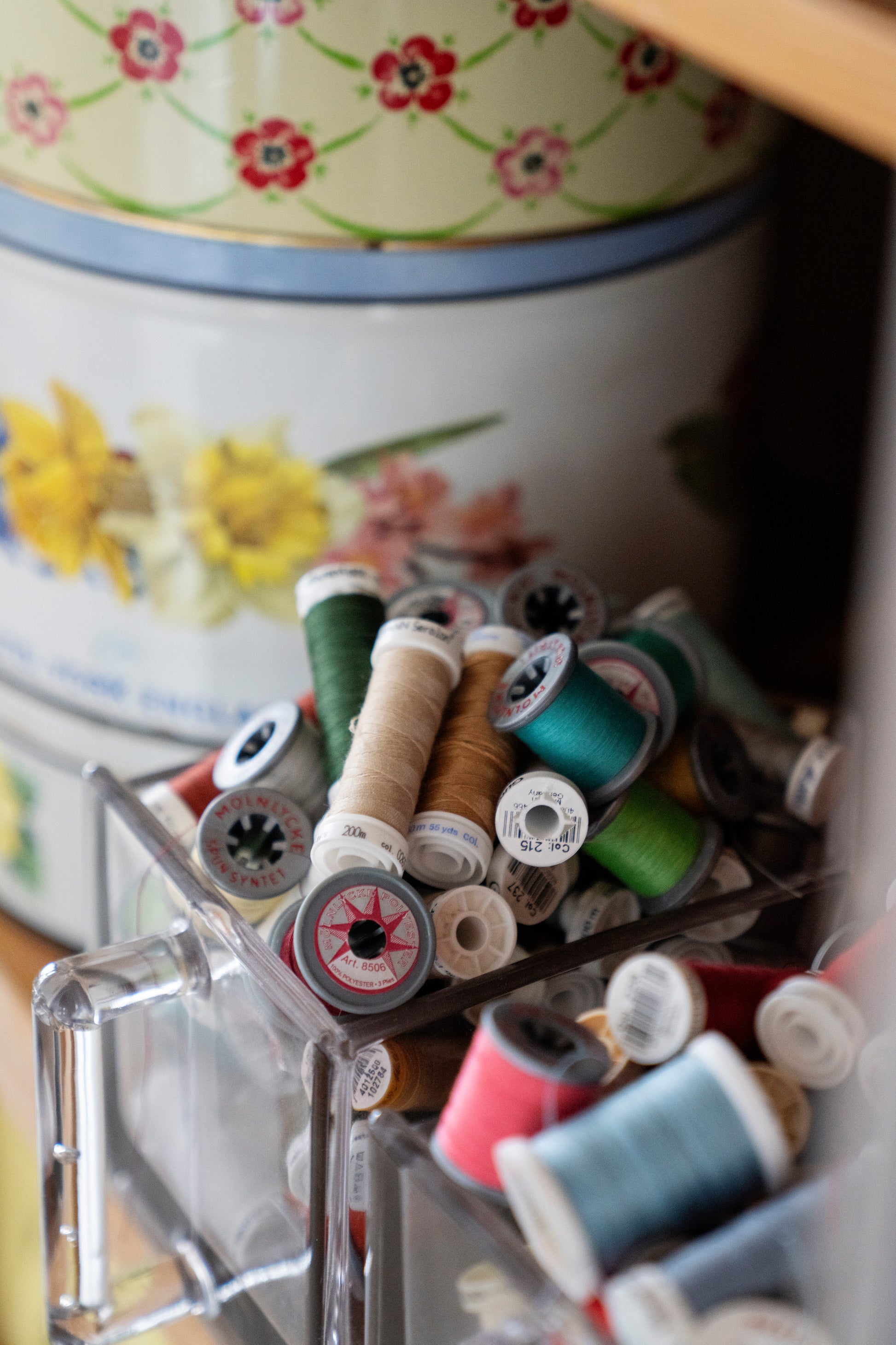 Bildet viser bokser med syutstyr og trådsneller og illustrerer gaverkort på produkter, symønster og sykurs hos nøysøm.